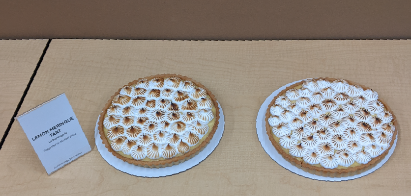 Two lemon meringue tarts on a table, each with perfectly piped and bruleed meringue