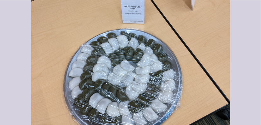 A tray holds a spiral of white and green rice cakes filled with sweet bean paste
